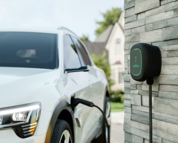 electric car plugged in to a home EV charger wallbox mounted to wall